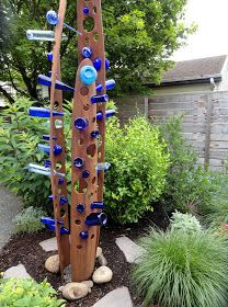 a sculpture made out of wine bottles is in the middle of a flower bed outside