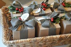 several wrapped presents are sitting in a wicker basket with holly and ribbons on them