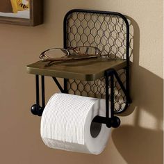 a pair of glasses is hanging on the wall next to a toilet paper roll holder