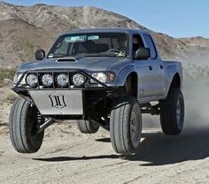 a silver truck driving down a dirt road