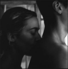 a man and woman kissing each other in black and white photo with the background blurry