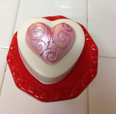 a heart shaped cake sitting on top of a red plate next to a white tile floor