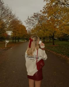 a woman standing on the side of a road drinking from a cup