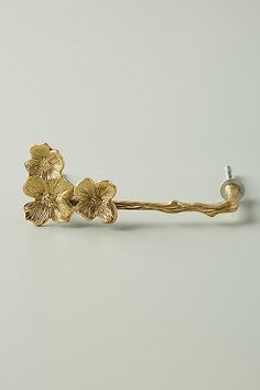 a pair of gold colored flowers on a white surface with a screw in the middle