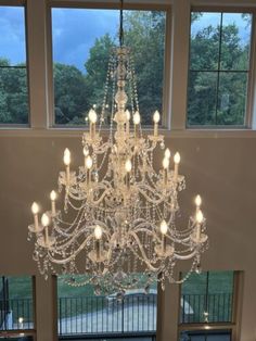 a chandelier hanging from the ceiling in a room with large windows and doors