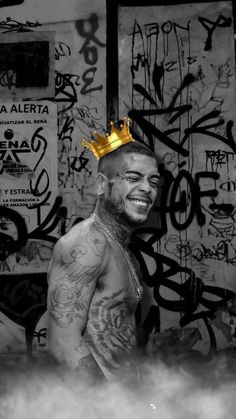 a man with a crown on top of his head in front of graffiti covered walls