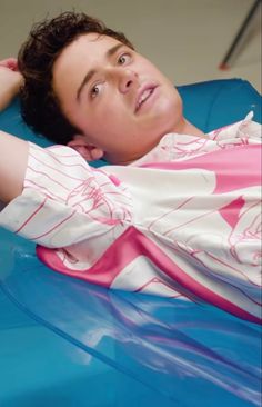 a young man laying on top of a blue car