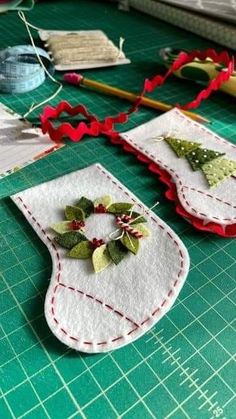 two christmas stockings are sitting on a table with scissors and sewing needles next to them