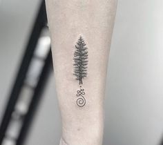 a small pine tree tattoo on the left inner forearm and arm with spirals around it