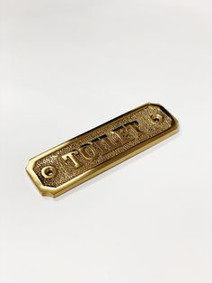 a gold tone metal name plate with the word totem on it's side