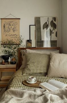 a coffee cup on a tray sitting on top of a bed next to a book