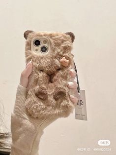 a person holding up a cell phone case with a teddy bear on it's back