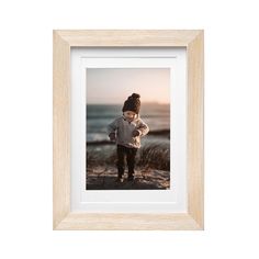 a framed photograph of a young boy standing on the beach