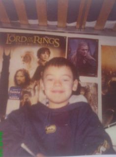 a young boy is sitting in front of posters