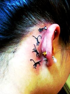 a woman's behind the ear tattoo with small dogs on her left side piercing