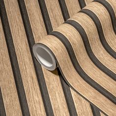 a striped wallpaper with black and brown stripes on it's surface, next to a roll of tape