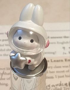 a silver can with a white rabbit on it's head sitting next to an open book