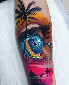 an eye with a rainbow and palm tree on the side of his arm is shown