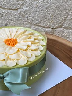 a cake decorated with white flowers on top of a wooden table next to a brick wall