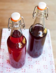 two glass bottles filled with liquid sitting on top of a table