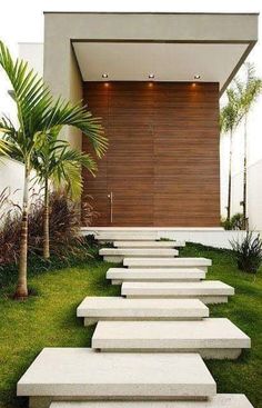 some concrete steps in front of a house with palm trees and grass on the ground