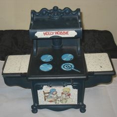 an old fashioned toy stove with four burners on it's sides and the words holly hubbie written on top