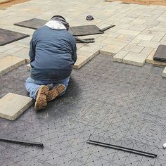 a man sitting on the ground working on some tiles