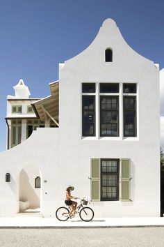 a person riding a bike in front of a white building