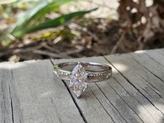 a diamond ring sitting on top of a wooden table next to a leafy plant