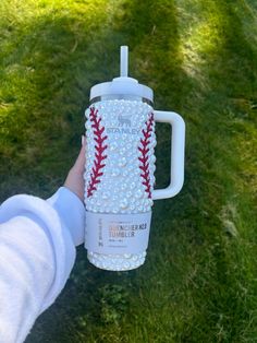 a person holding a baseball shaped coffee cup