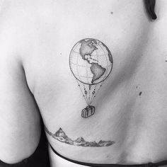 the back of a woman's shoulder with a tattoo on it that has an image of a hot air balloon flying in the sky