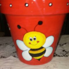 a red pot with a smiling bee painted on it