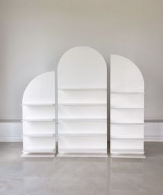 two white bookcases sitting side by side in an empty room