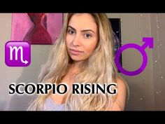 a woman with long blonde hair standing in front of a purple and white sign that reads scorpio rising