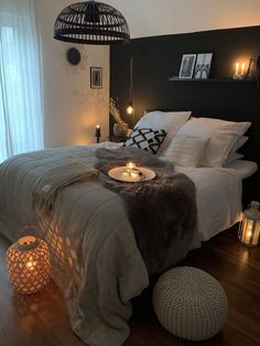 a bedroom with a large bed and candles on the nightstands in front of it