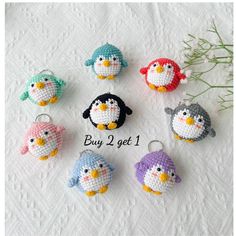 small crocheted penguin keychains are displayed on a white tablecloth with flowers in the background