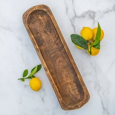 a wooden tray sitting on top of a marble counter next to lemons and leaves