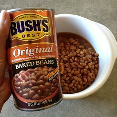 a person holding a can of baked beans