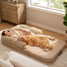 a woman laying on top of a dog bed in a living room next to a window