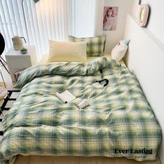 a green plaid comforter on a bed in a room with white walls and wooden floors