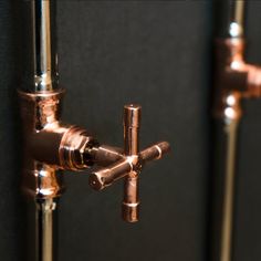 there are two faucets on the wall in this bathroom shower stall, one is copper and the other is black