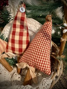 two red and white checkered pillows sitting on top of a basket next to a christmas tree