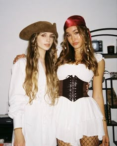 two beautiful young women standing next to each other wearing pirate costumes and headgear