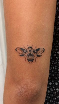 a small bee tattoo on the arm