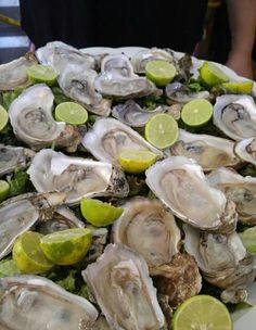 a platter filled with oysters and lime wedges