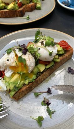 an avocado toast with poached eggs and tomatoes is on a plate