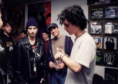 a group of young men standing next to each other in front of a wall with posters on it