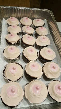 cupcakes with pink frosting are sitting in a pan on top of a table