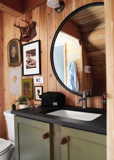 a bathroom with wood paneling and pictures on the wall, including deer head mounted to the wall