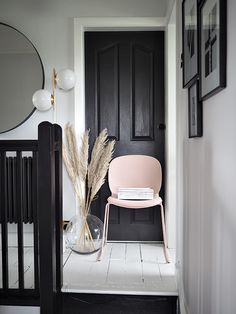 a pink chair sitting in front of a black door